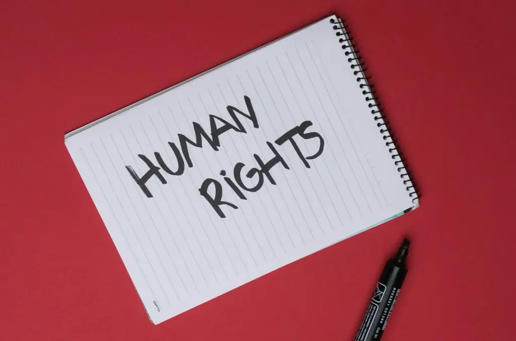 Notepad on red background with 'Human Rights' written, highlighting social justice.