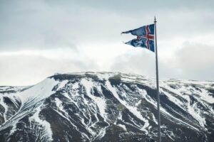 Icelandic flag flying against a backdrop of snow-covered mountains, capturing Iceland's natural beauty.