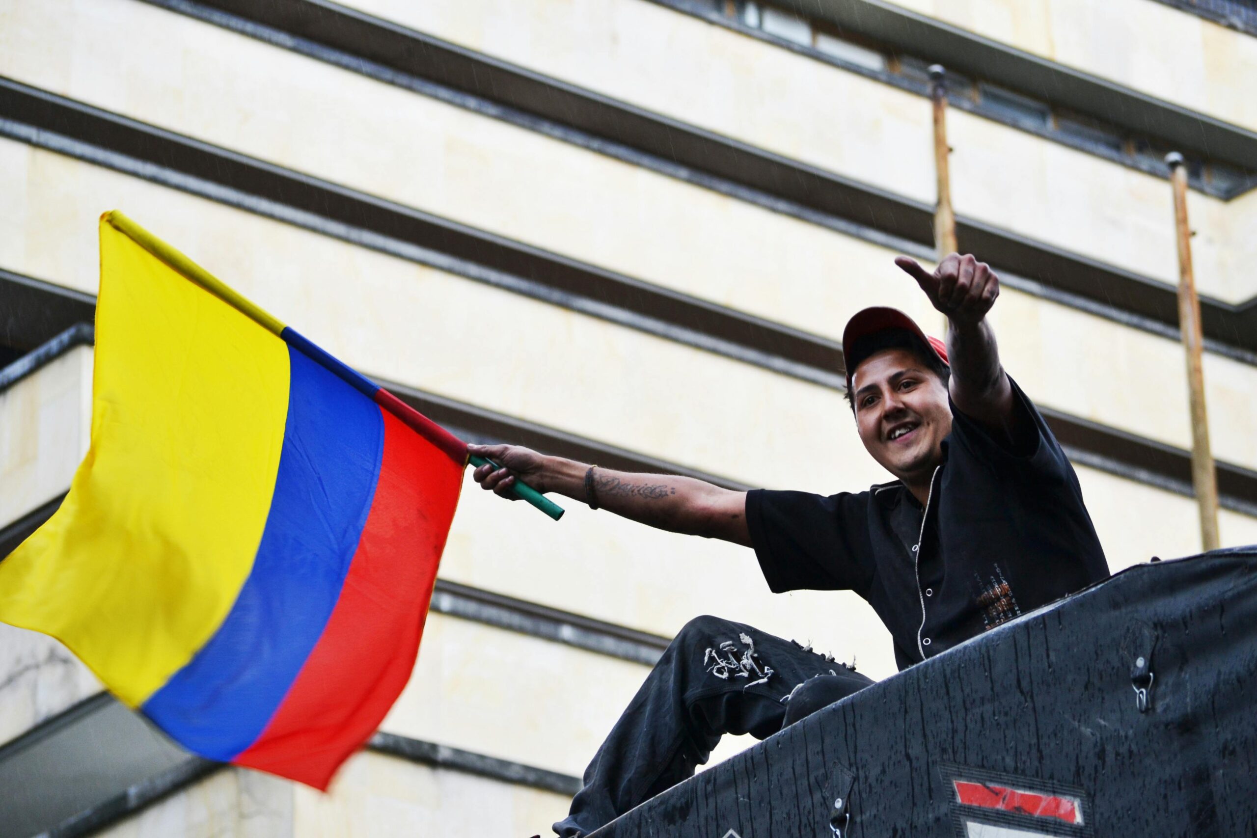 A man joyfully waves the Colombian flag in Bogotá, showing national pride.