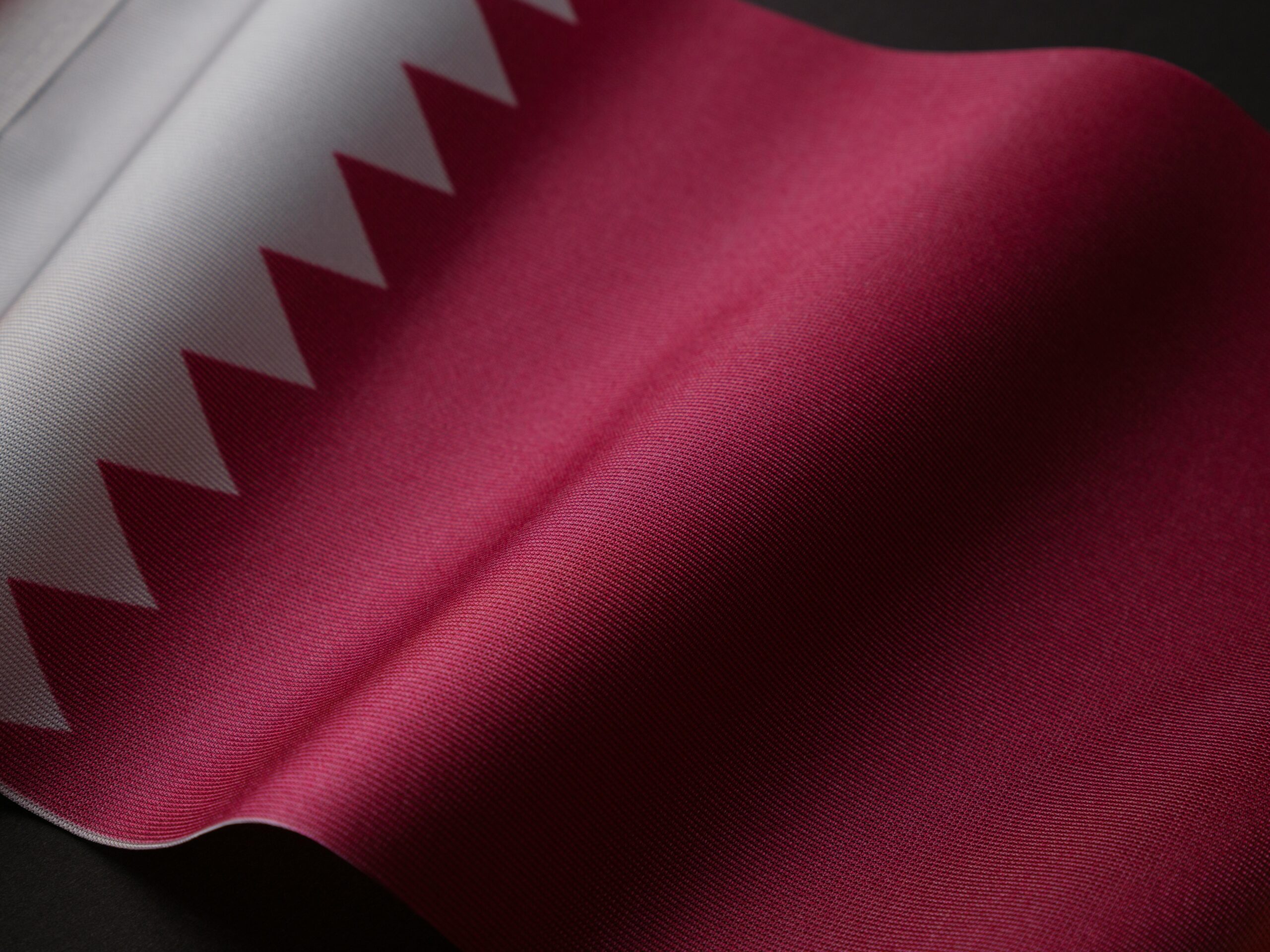 A detailed close-up of the Qatar national flag showcasing its unique design and colors.