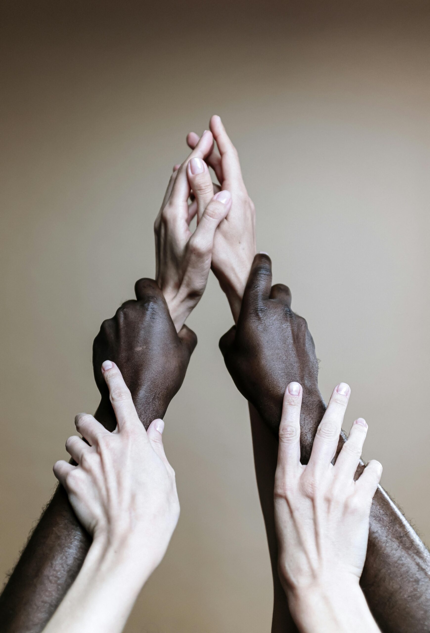 Multiple hands of different ethnicities reaching up, symbolizing unity and togetherness.