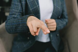 Crop anonymous female in classy outfit showing crossed fingers to camera while sitting in armchair and communicating with hand language