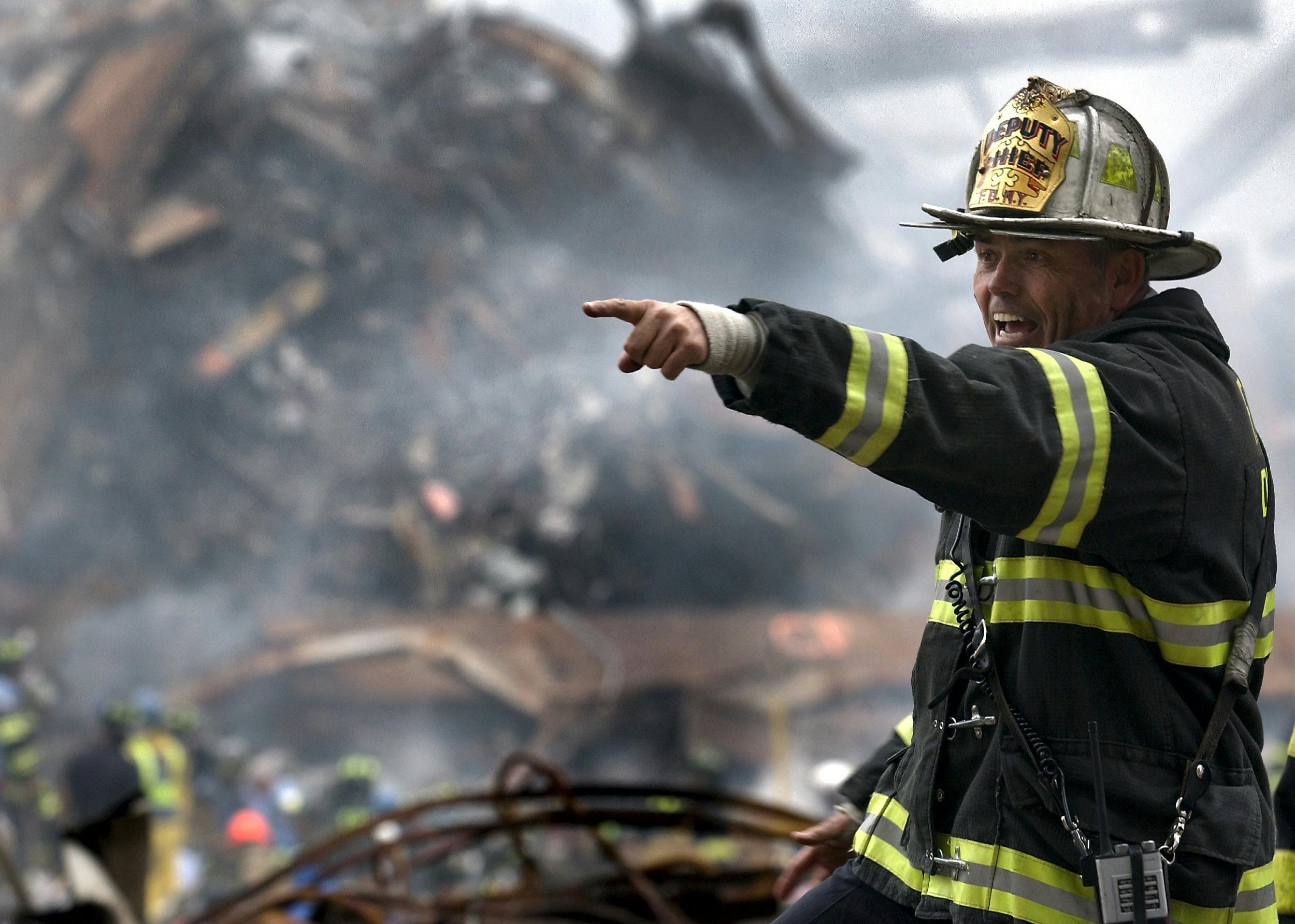 A firefighter in action at a disaster scene, directing rescue operations amidst smoke and debris.